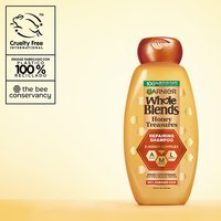 Garnier Whole Blends Honey Treasures Repairing Shampoo hero shot: highlighting cruelty-free international certification, the bee conservancy partnership, and a bottle made of 100% recycled plastic.