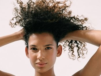 A woman with curly hair demonstrates the "plopping" method.