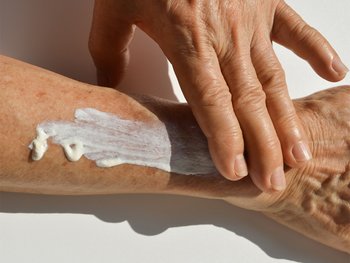 A hand applying lotion to an arm.