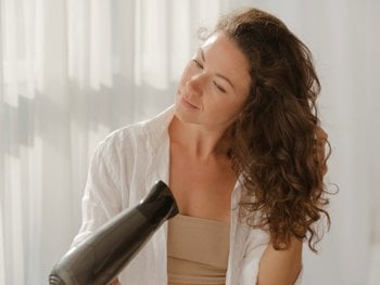 Woman blowing drying her long wavy hair