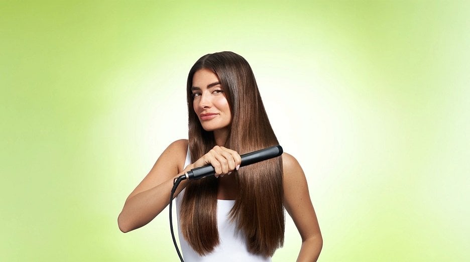 Brunette model facing forward as she straighten long, thick, smooth hair.