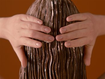 Woman applying conditioner to her hair in the shower.