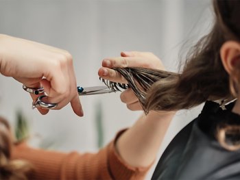 Human hands hair cut using scissors.