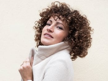 A woman with voluminous, shoulder-length curly hair.