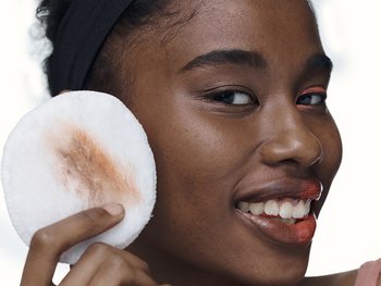 Person applying product to their face with a cotton round.