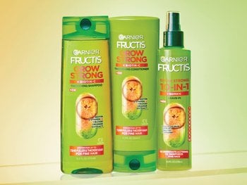 Three green Garnier Fructis Grow Strong products: Thickening Shampoo, Thickening Conditioner, and a 10-in-1 Leave-in, all featuring Biotin-C + Blood Orange Extract for fine hair.