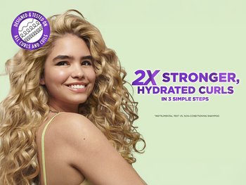 Girl with 3C curls smiling swinging her head to the side.