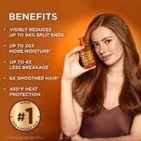 A woman holding a bottle of Garnier Honey Treasures leave-in treatment serum.